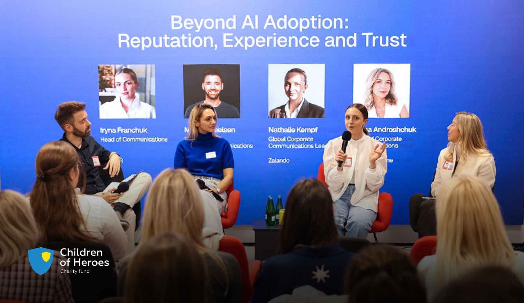 A panel discussion titled “Beyond AI Adoption: Reputation, Experience and Trust” at the Employer Branding Community event in Warsaw. Four speakers sit in red chairs in front of an audience. One of them is speaking into a microphone.