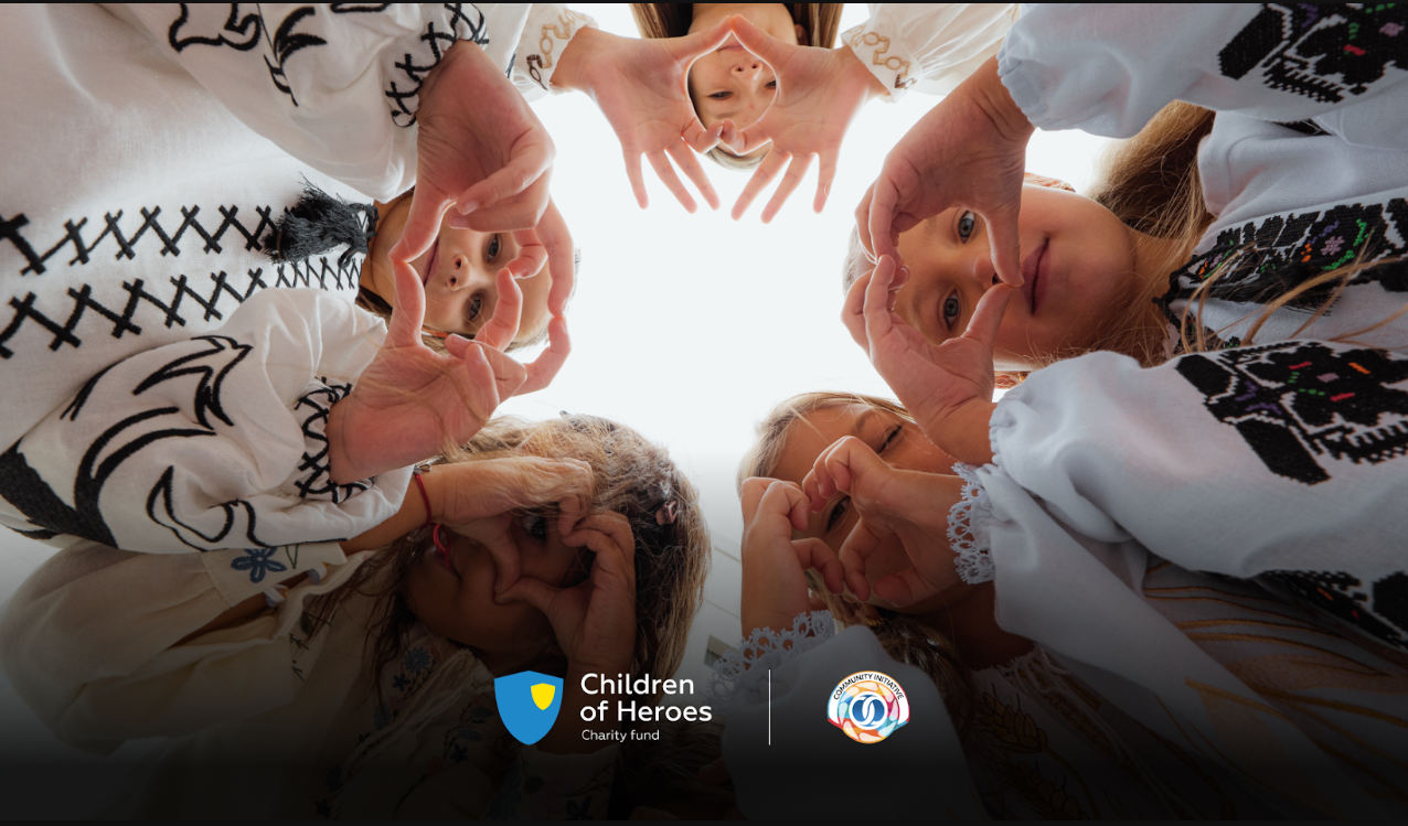 Five children in embroidered Ukrainian vyshyvanka shirts stand in a circle and look down into the camera, each making a heart shape with their hands. Children of Heroes Charity Fund and Community Initiative logos at the bottom